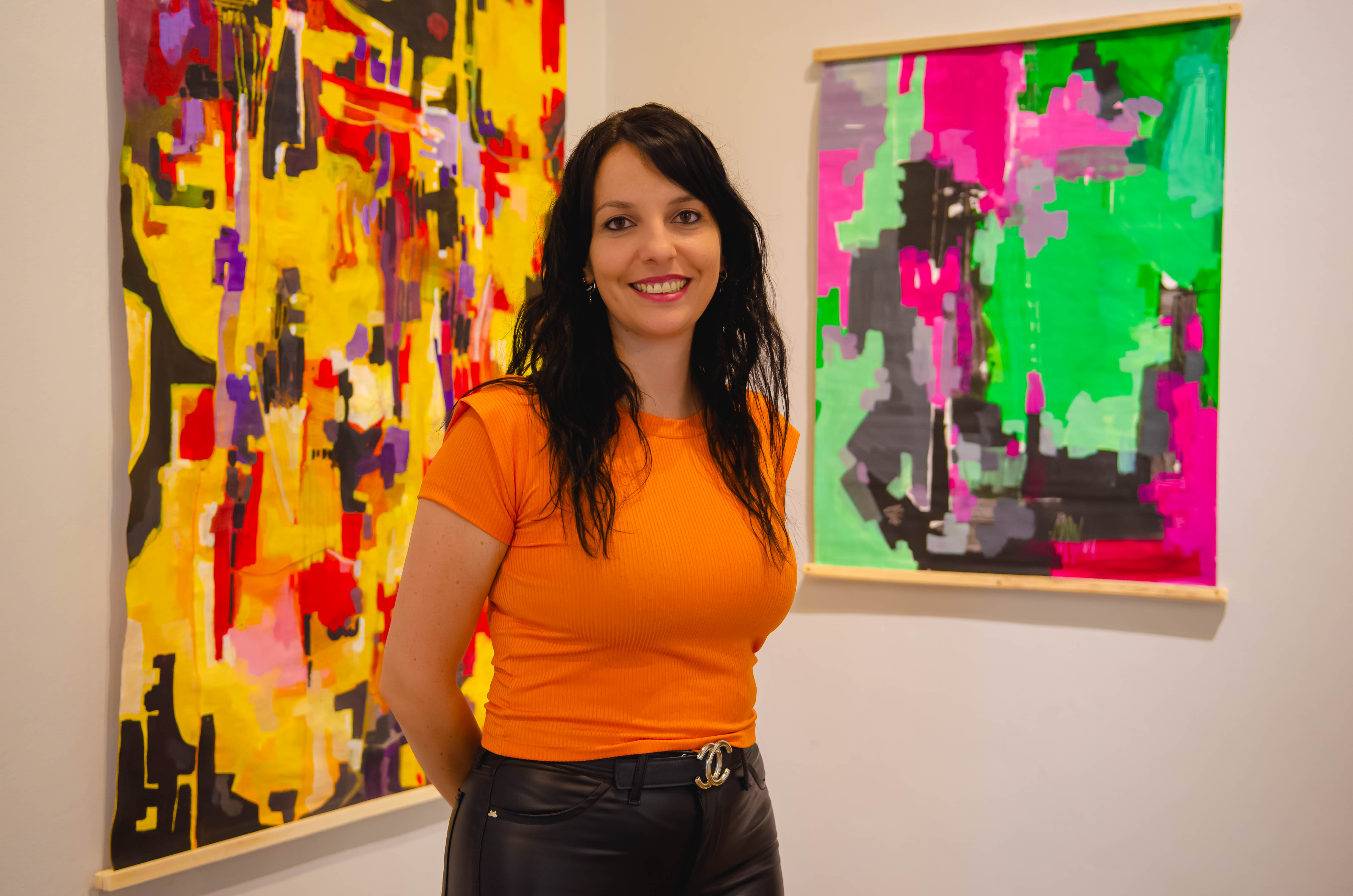 Evelin Puri junto a obras pictóricas de su autoría